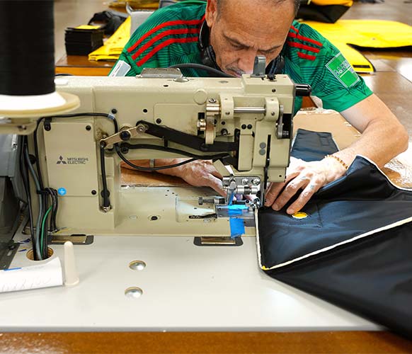 LJD employee using sewing machine on a Eyewash Station Heater Jacket​
